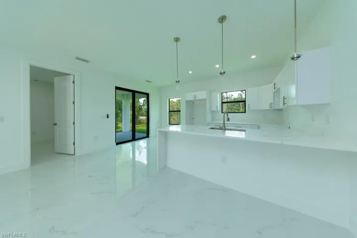 Modern kitchen featuring white cabinetry, a large kitchen island with a white countertop, and recessed lighting