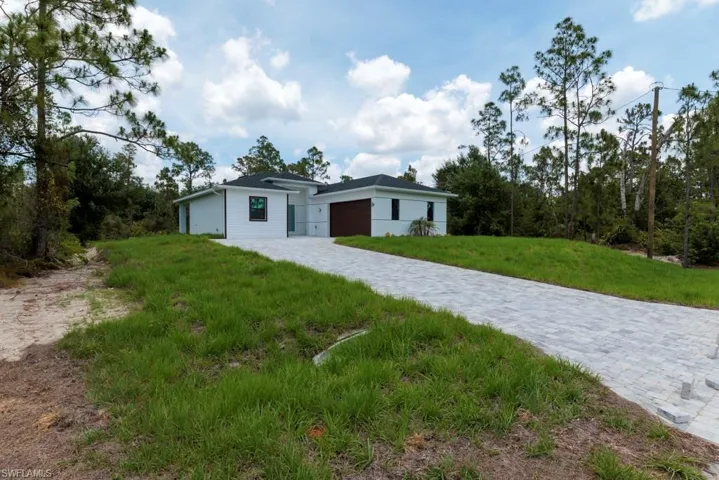 Contemporary white exterior with a dark roof and a paver driveway