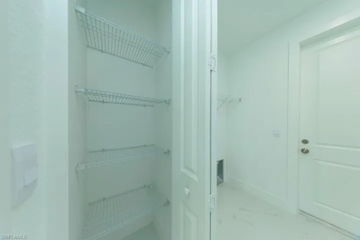 Utility space featuring wire shelving, a paneled door, and light-toned flooring