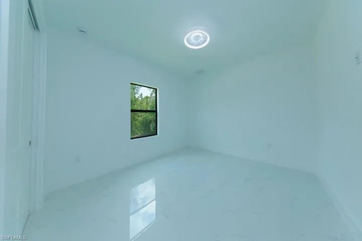 Bright interior space featuring a window with black trim, a contemporary ceiling light fixture, and white walls