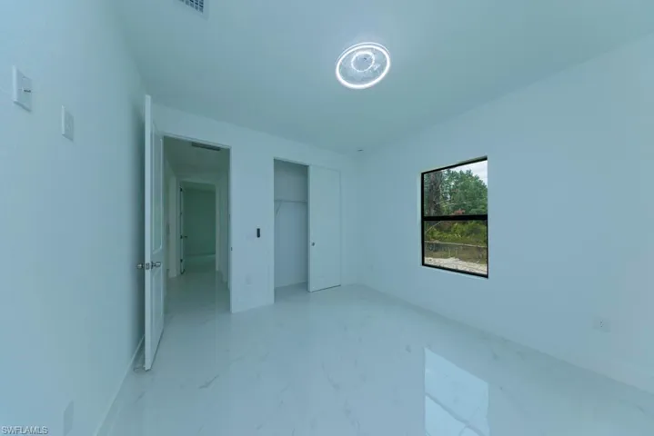 Bright interior room featuring white walls and large format tile flooring