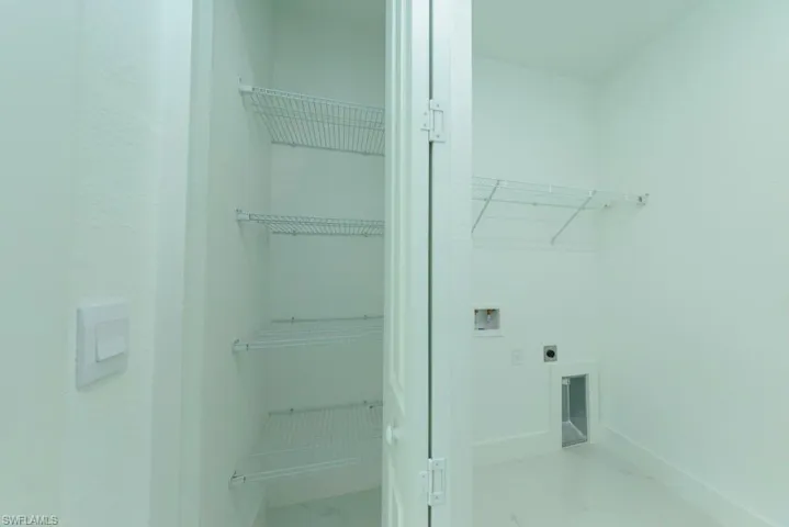 Utility room with wire shelving, wall-mounted outlets, and a floor vent