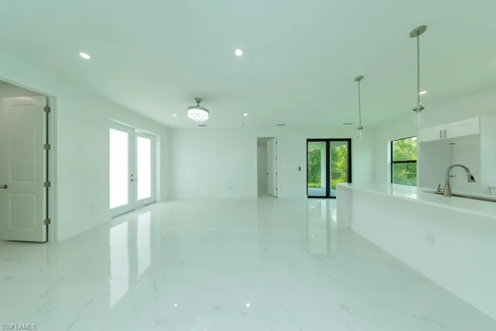 Spacious open-concept interior featuring large format marble-look tile flooring, recessed lighting, and a crystal chandelier