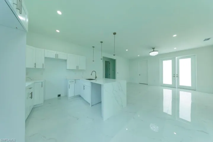 Modern kitchen with white cabinetry and an oversized island featuring a waterfall countertop