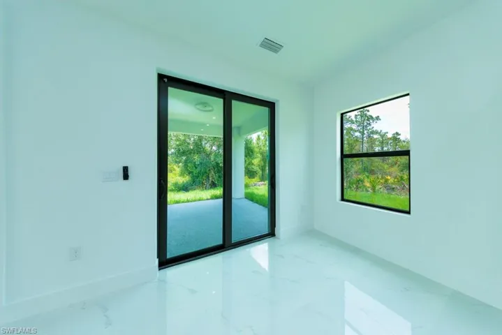Spacious interior featuring white walls, white-finish flooring, a large sliding glass door, and a single-pane window