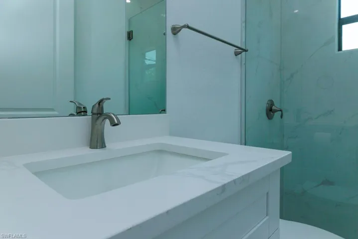 Vanity featuring an integrated sink, brushed nickel faucet, and a light-toned countertop with subtle veining