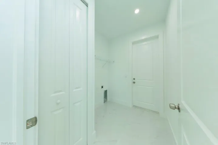 Utility room featuring white walls, white paneled doors, recessed lighting, and tile flooring