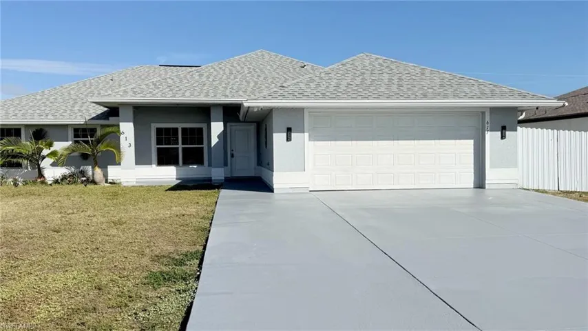 Ranch-style house featuring a shingled roof, stucco siding, driveway, an attached garage, and a front lawn