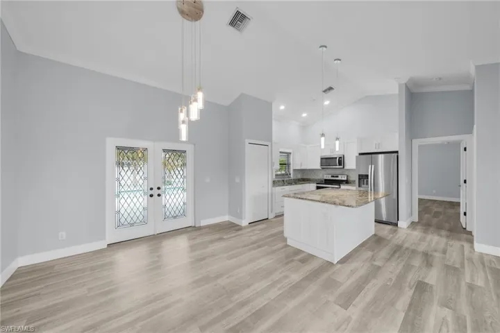 Kitchen with french doors, pendant lighting, appliances with stainless steel finishes, a center island, and white cabinets