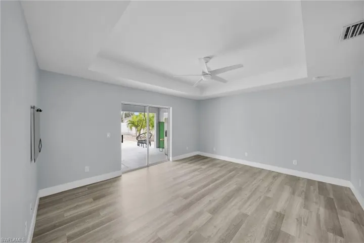 Spare room with a tray ceiling, light wood-style flooring, and a ceiling fan