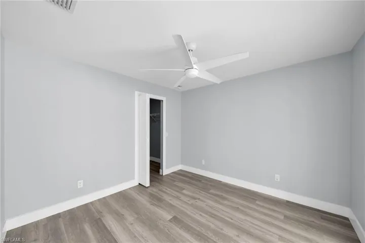 Unfurnished bedroom with a ceiling fan, light wood-type flooring, and a spacious closet