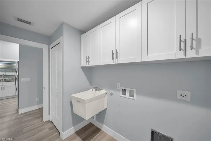 Washroom featuring hookup for a washing machine, light wood-style floors, and cabinet space
