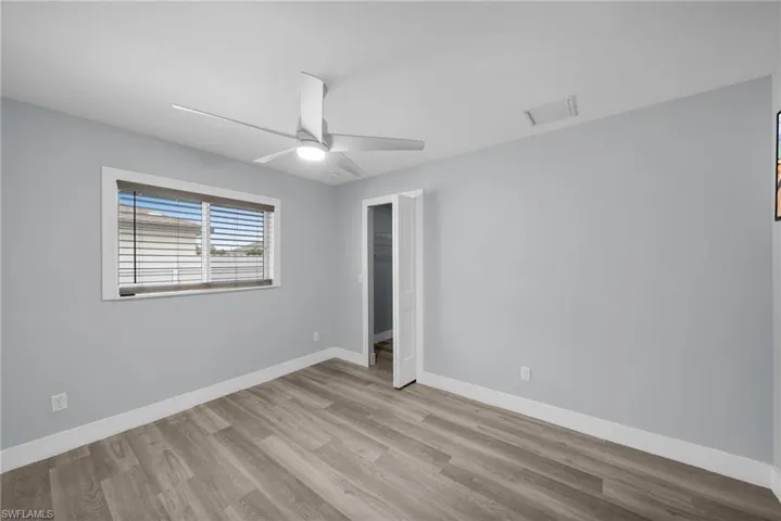 Unfurnished bedroom featuring attic access, a ceiling fan, light wood-type flooring, and a spacious closet