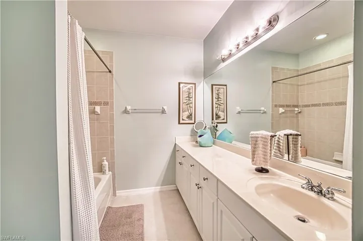 Bathroom featuring an extended vanity with an integrated sink, polished chrome faucet, and a large wall-mounted mirror