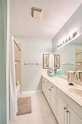 Bathroom featuring a double vanity with white cabinetry, integrated sink, and an extended mirror