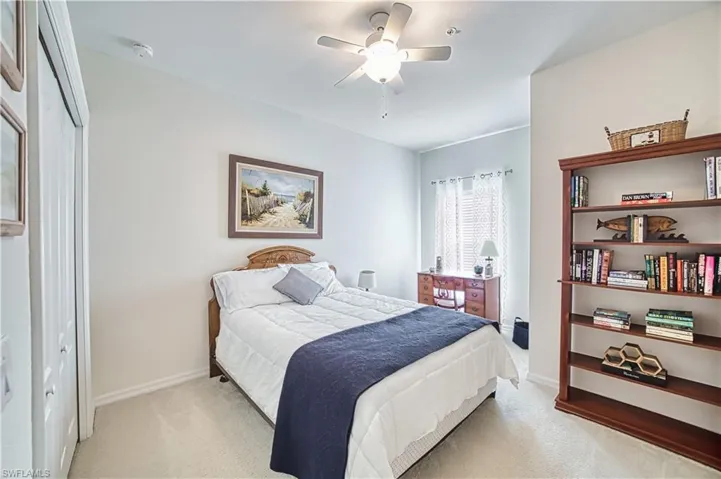 Carpeted room featuring a ceiling fan with light, a window with sheer curtains, a built-in closet with bifold doors, and light-toned walls