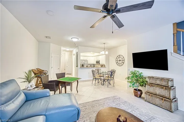 Open-concept living space featuring light-toned tile flooring, recessed lighting, and a ceiling fan