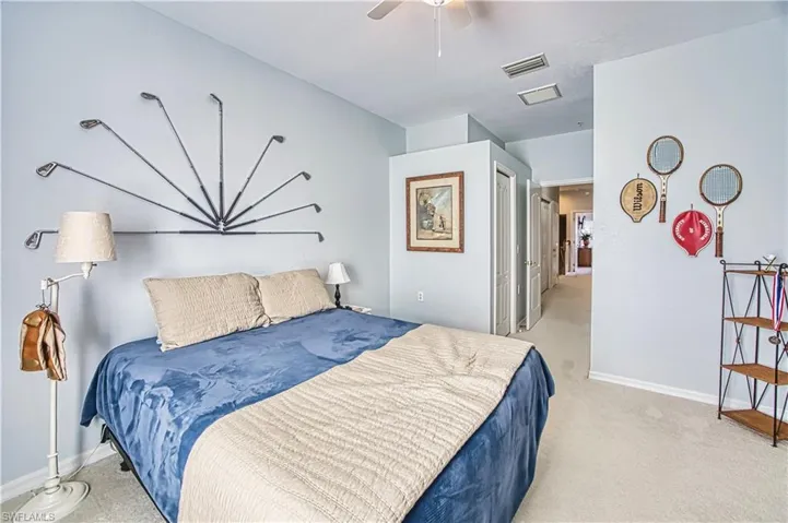 Carpeted bedroom featuring light blue walls, a ceiling fan, and a hallway entry