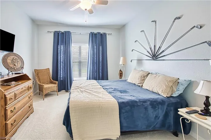 Carpeted bedroom with a ceiling fan, a window with blinds and blue curtains, and light-colored walls