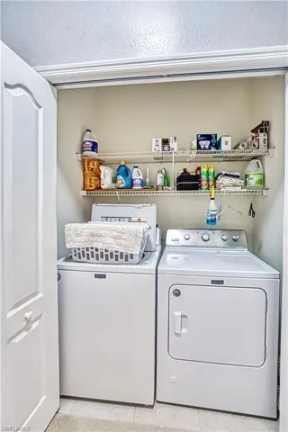 Dedicated laundry area featuring a white bi-fold door, overhead wire shelving, and tiled flooring