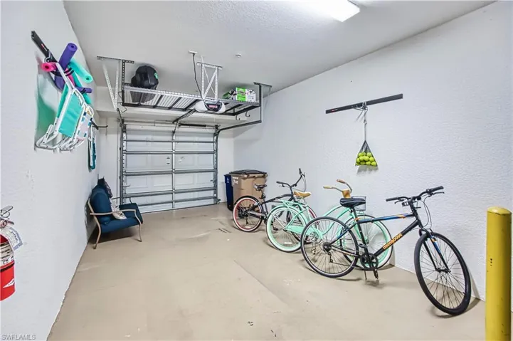 Spacious garage featuring an automatic overhead door, concrete flooring, and ample overhead storage racks