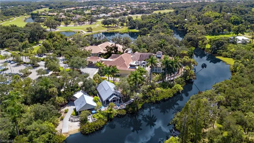 Expansive property featuring a winding waterway, lush mature trees, and multiple structures with distinct architectural styles