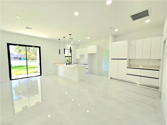 Kitchen with modern cabinets, white cabinetry, pendant lighting, recessed lighting, and light marble finish floors