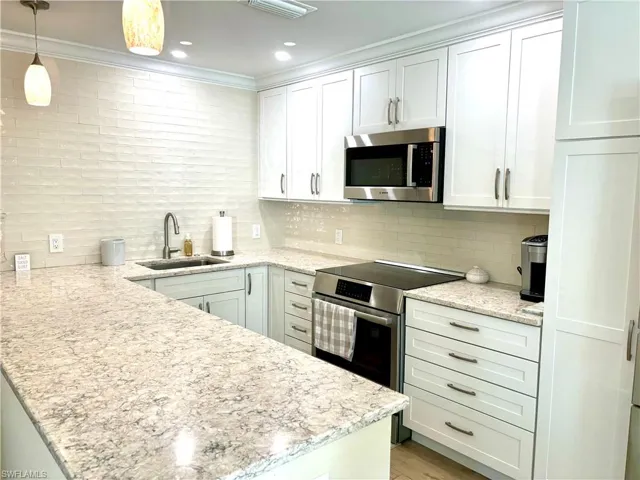 Modern Kitchen featuring stainless steel high-end appliances, decorative backsplash, large peninsula, white cabinetry.