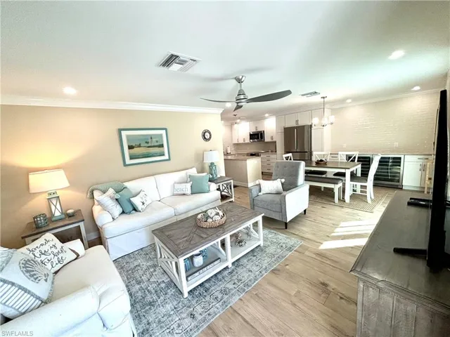 Living room featuring open floor plan, recessed lighting, ornamental molding, light wood-style flooring, ceiling fan