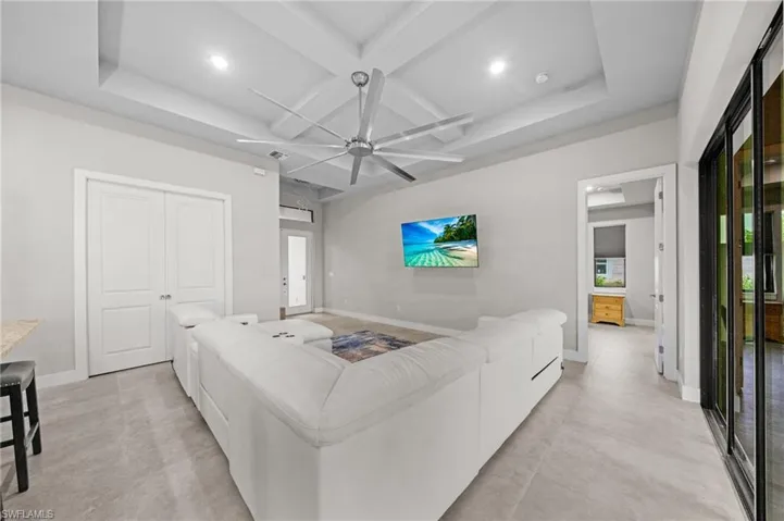 Kitchen with blue cabinets, light stone counters, decorative light fixtures, coffered ceiling, and appliances with stainless steel finishes
