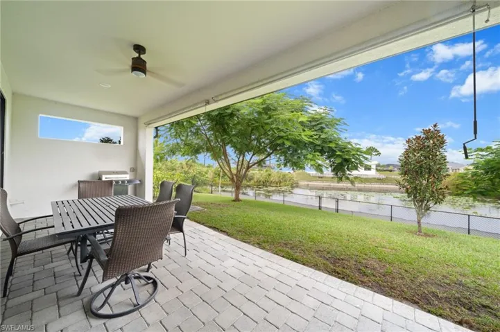Rear view of property featuring roof with shingles, stucco siding, a lawn, and a patio area