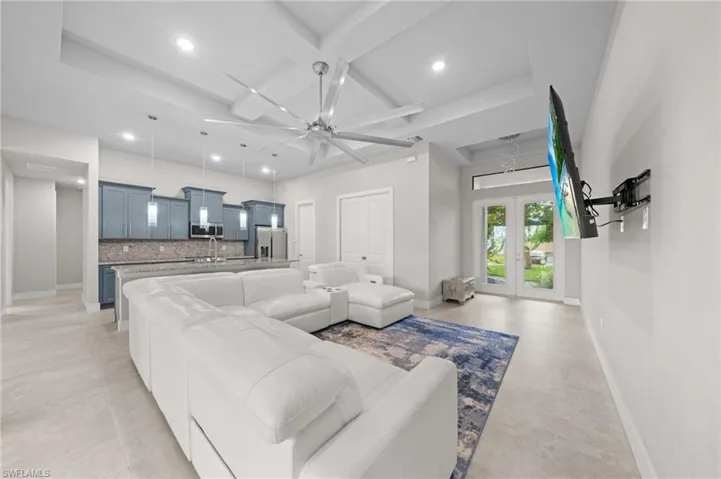 Kitchen with light stone countertops, decorative light fixtures, blue cabinets, open floor plan, and an island with sink