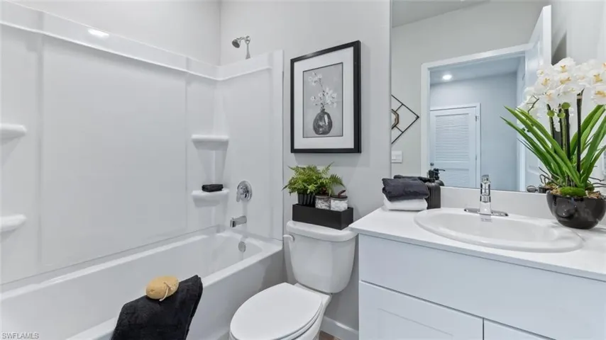 Model home. Full bath featuring vanity and washtub / shower combination