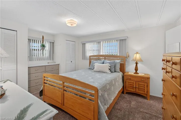 Carpeted bedroom with multiple windows and multiple closets