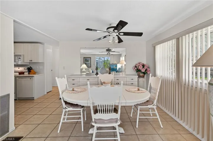 Dining room with ceiling fan and light tile patterned floors. Wall of windows for cheerful brightness.