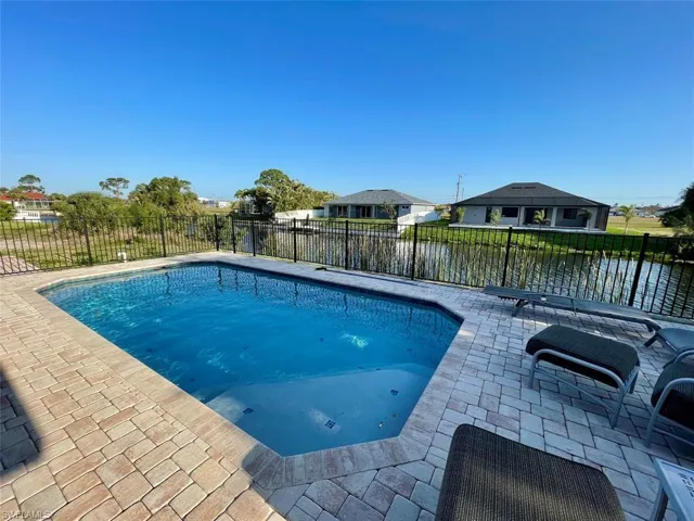 View of swimming pool featuring a fenced in pool, a water view, a fenced backyard, and a patio area