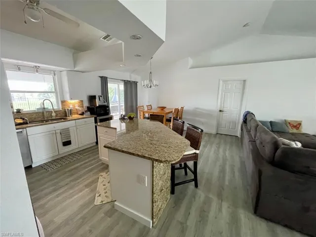 Kitchen featuring stainless steel dishwasher, a breakfast bar, open floor plan, a sink, and light wood finished floors