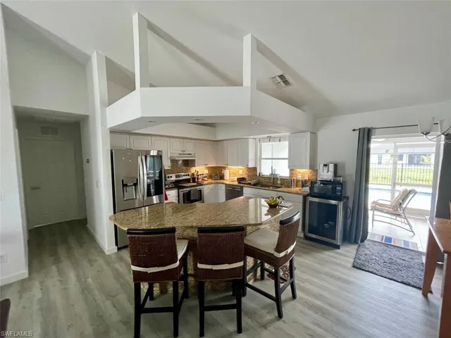 Kitchen with white cabinets, appliances with stainless steel finishes, light wood finished floors, a center island, and visible vents