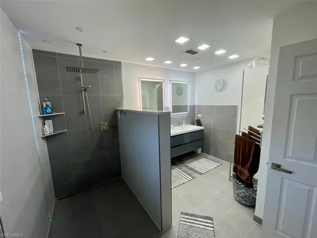 Full bathroom with a walk in shower, tile walls, tile patterned flooring, and vanity