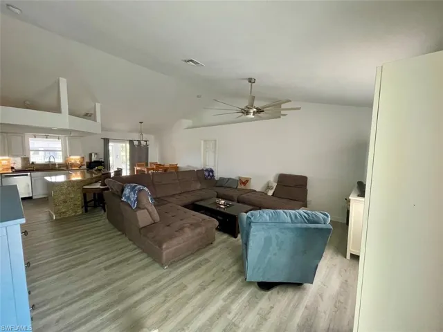 Living room with light wood-type flooring, a ceiling fan, lofted ceiling, and visible vents