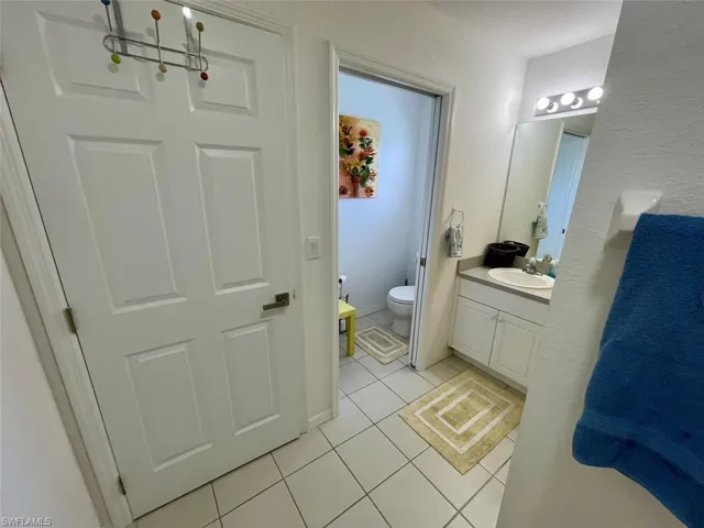Bathroom with toilet, a chandelier, tile patterned flooring, and vanity