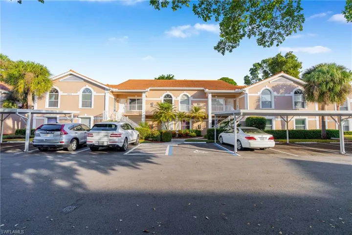 View of property featuring covered and uncovered parking and a residential view
