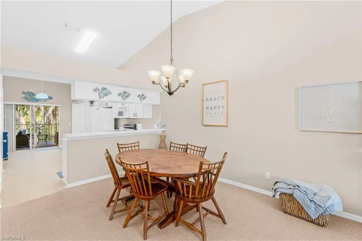 Dining room with light carpet, high vaulted ceiling, and a chandelier