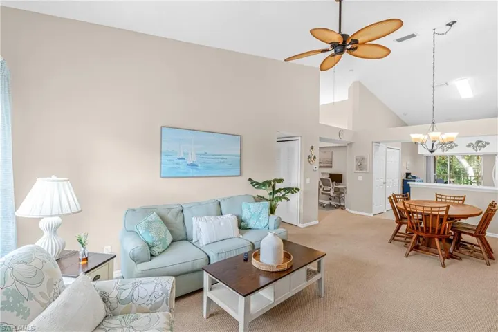 Living area featuring high vaulted ceiling, carpet flooring, a ceiling fan, and a chandelier