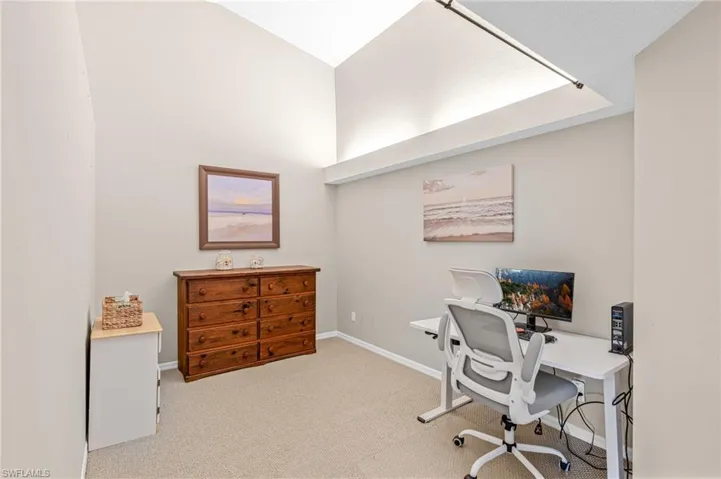 Home office with light colored carpet and lofted ceiling
