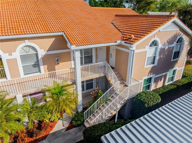 View of front of home featuring a tiled roof, stairway, and stucco siding