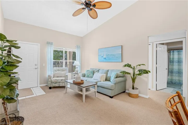 Living room with high vaulted ceiling, light carpet, and a ceiling fan