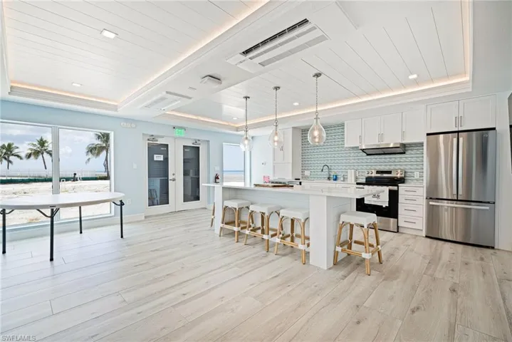 Kitchen featuring stainless steel appliances, wooden ceiling, a breakfast bar area, white cabinetry, and plenty of natural light