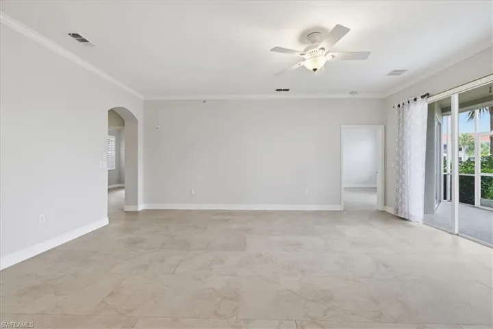Spacious room featuring tile flooring, crown molding, a ceiling fan with integrated lighting, and direct access to an outdoor screened area through sliding glass doors