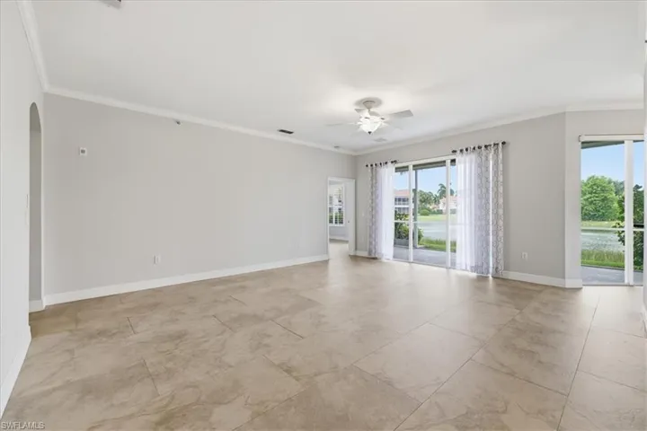 Spacious interior featuring large format tile flooring, crown molding, and light gray wall paint